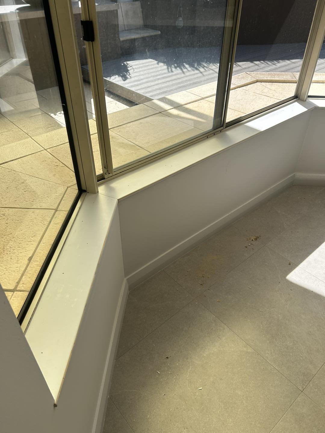 Bay window corner with white skirting boards along a tiled floor