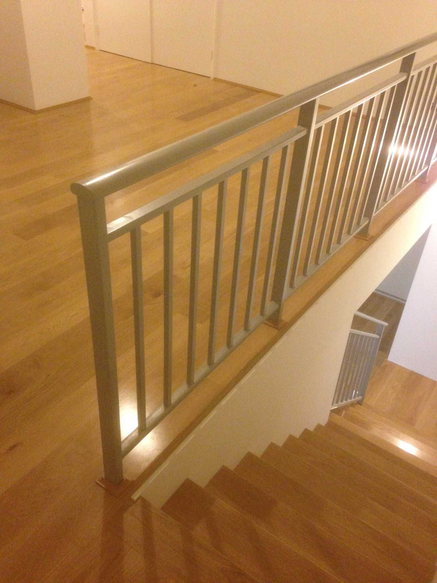 Timber staircase with a silver metal balustrade, seen from the landing