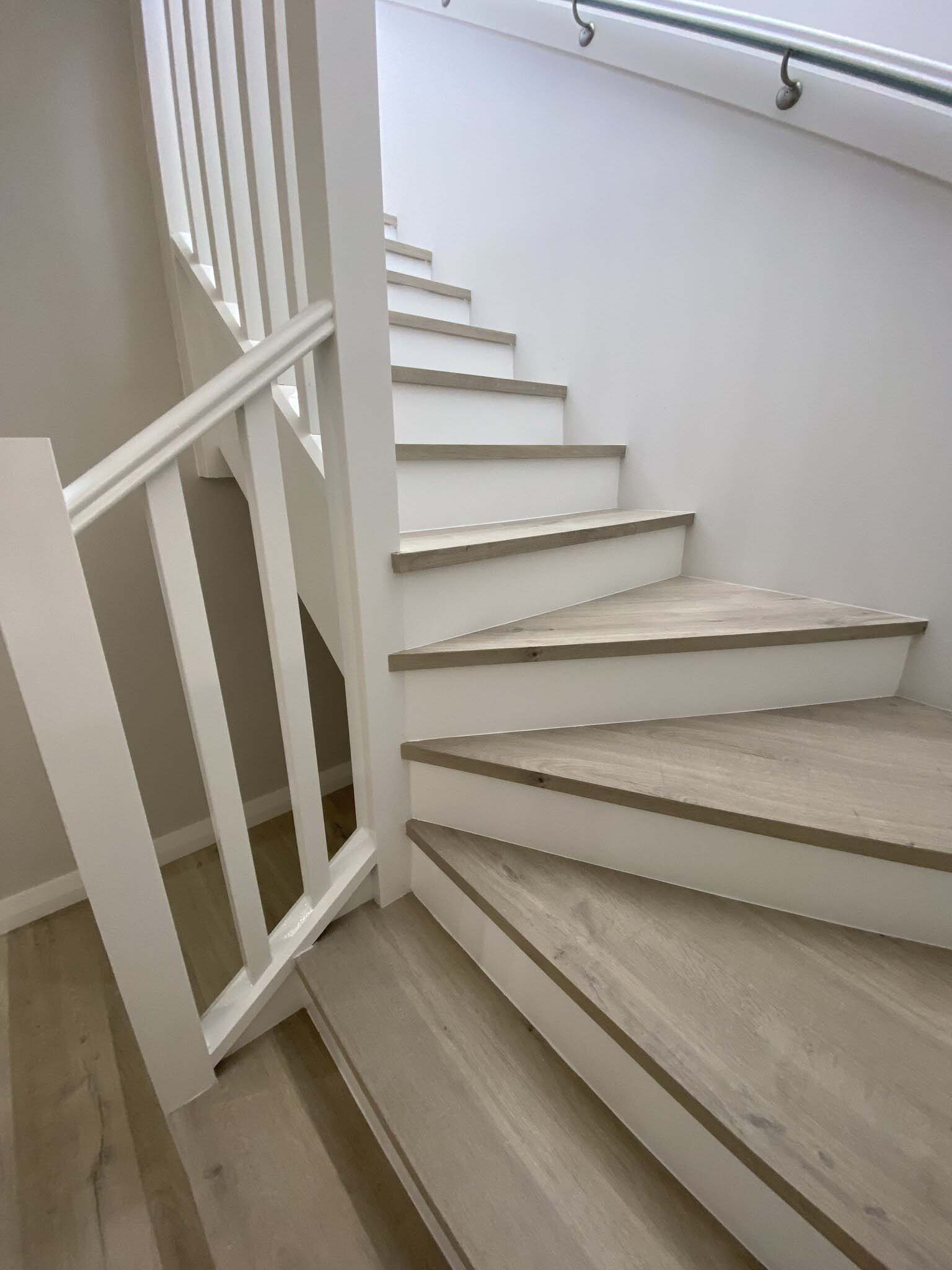 Winding staircase with light timber-look treads, white risers and balustrade
