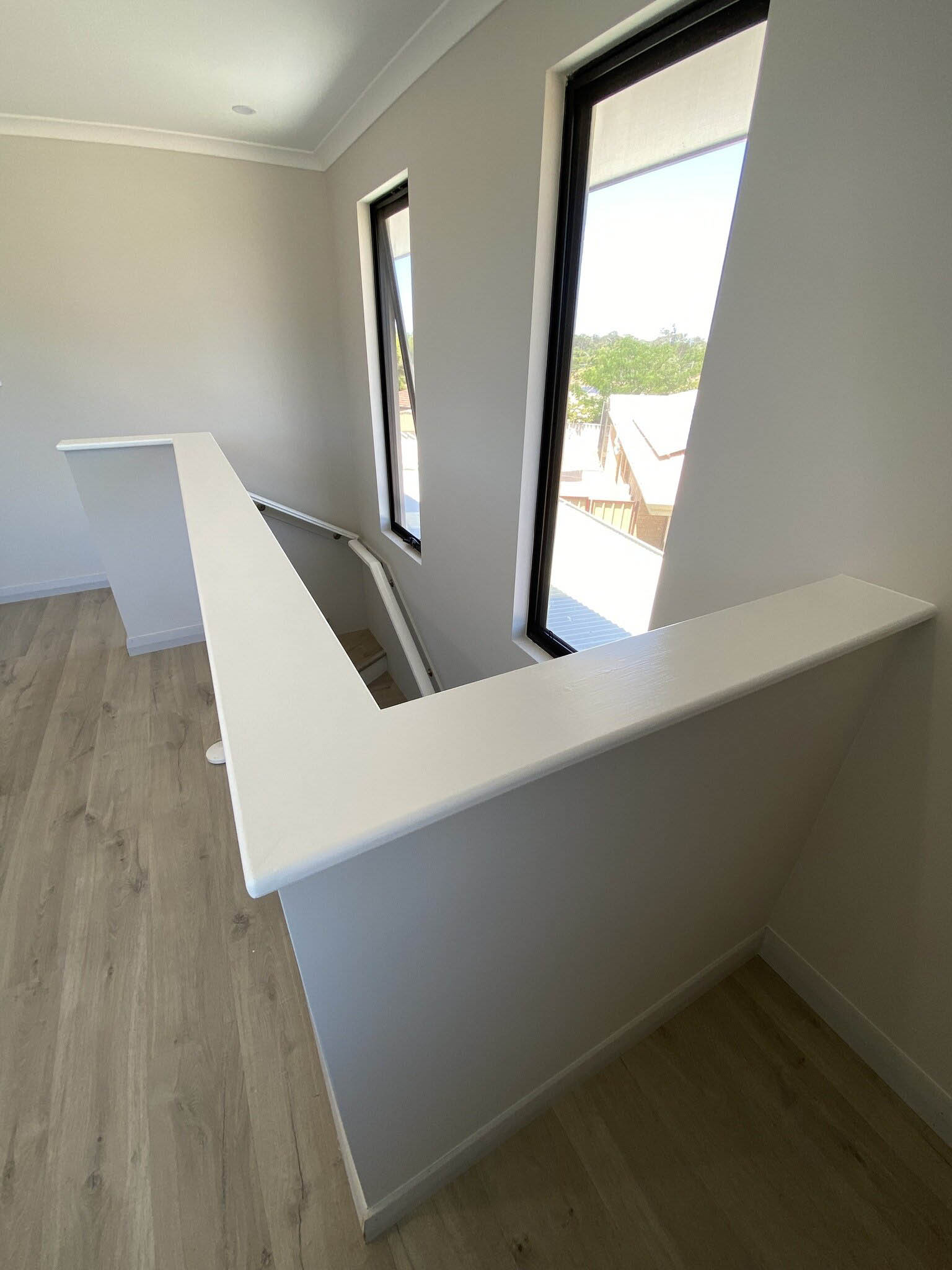 Upstairs landing with a white half-height wall and light timber-look floor