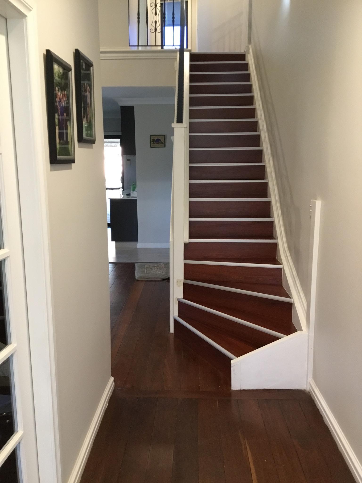 Hallway leading to a staircase with dark timber treads and white risers