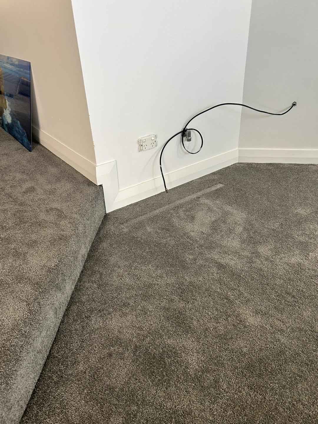 Grey carpet laid over a raised floor step, with white skirting boards