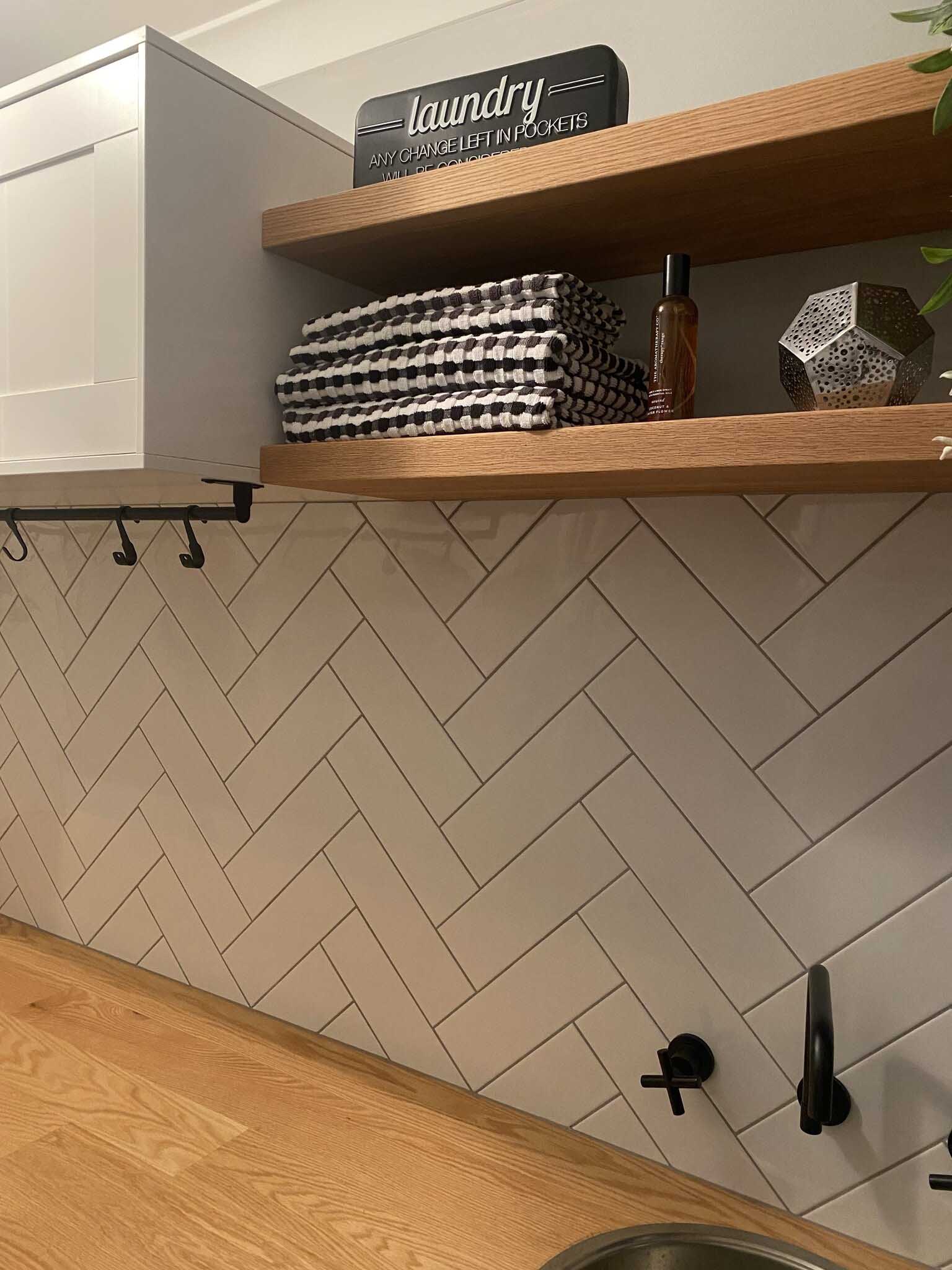 Floating timber shelves above a herringbone tile splashback in a laundry