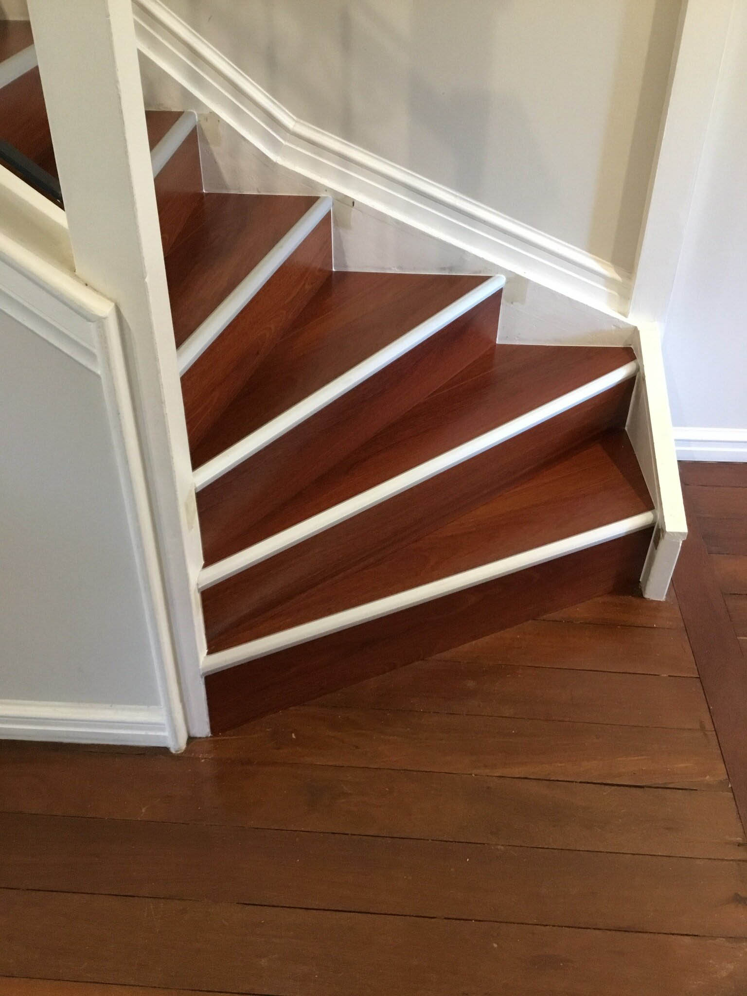 Winding staircase with red timber treads and white nosings