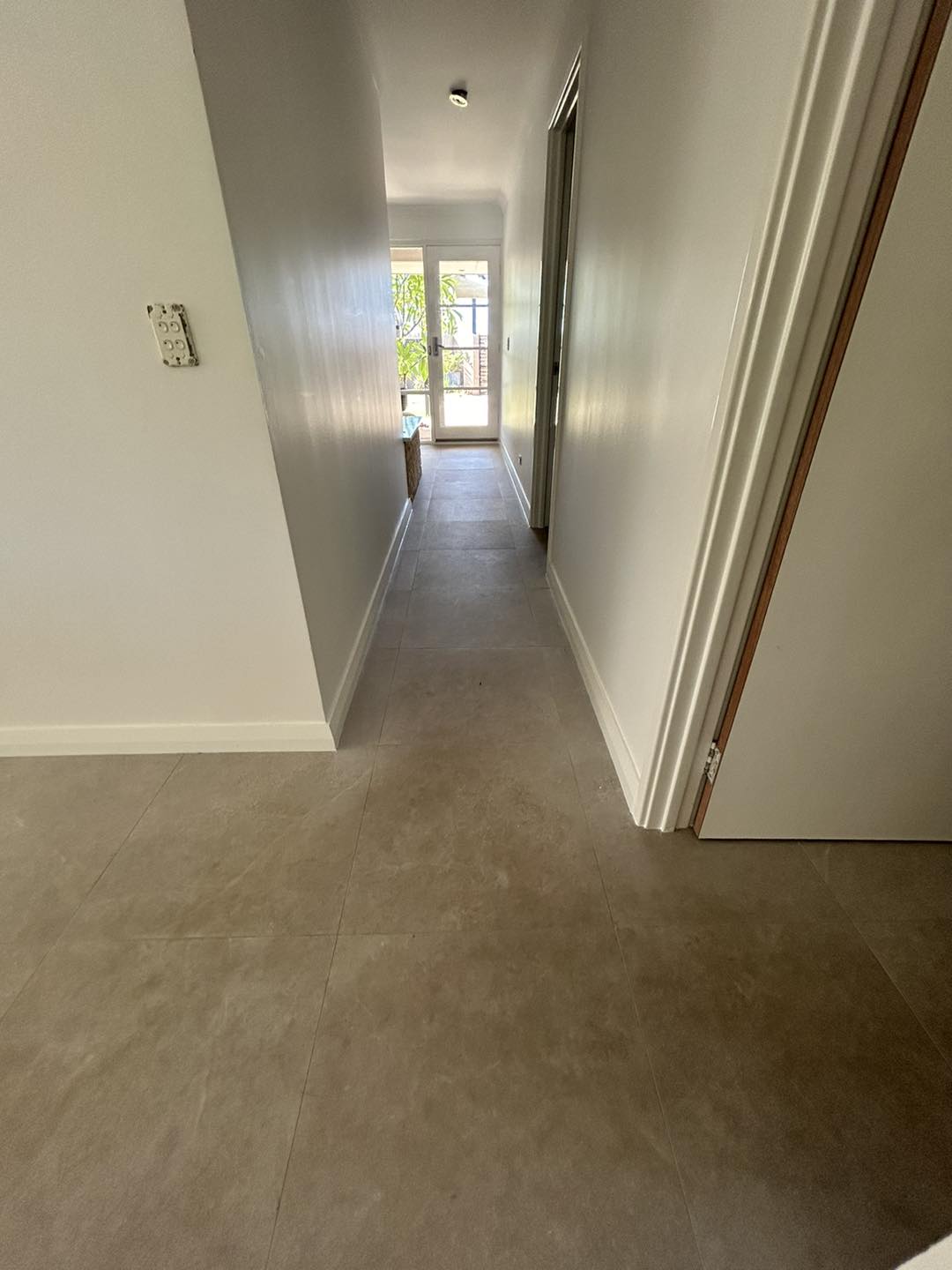 Long hallway with a grey floor and white skirting boards