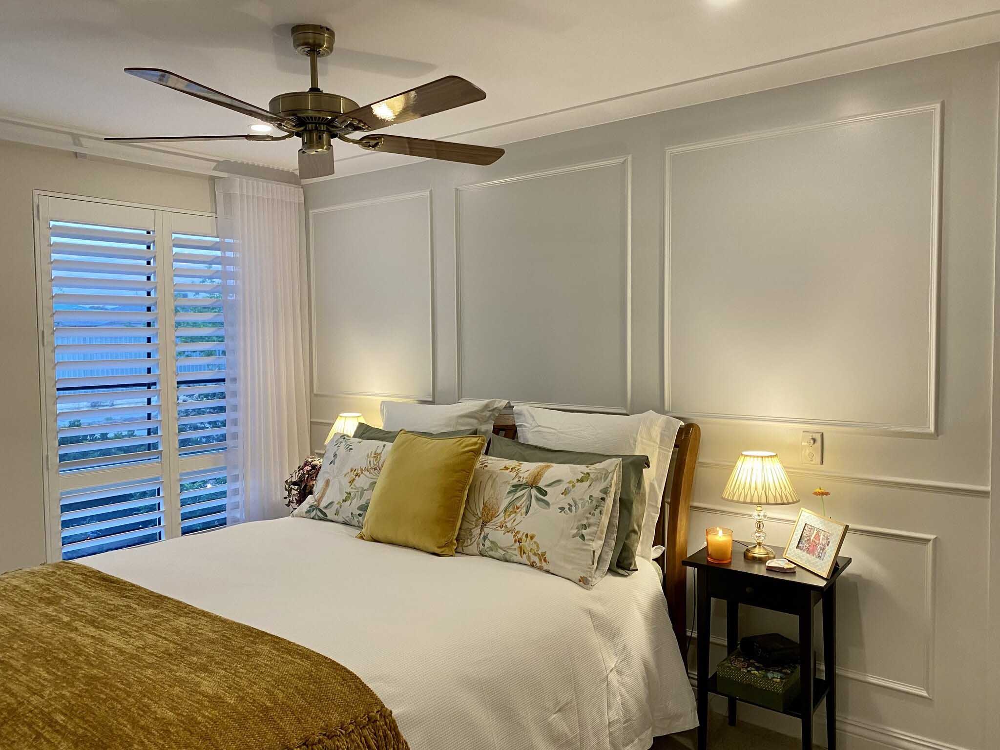 Bedroom with white panel moulding on the walls and plantation shutters