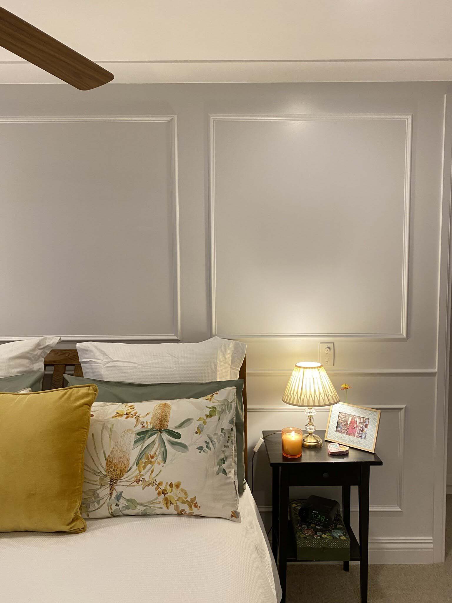 Close view of wall panel moulding beside a bedside table and lamp