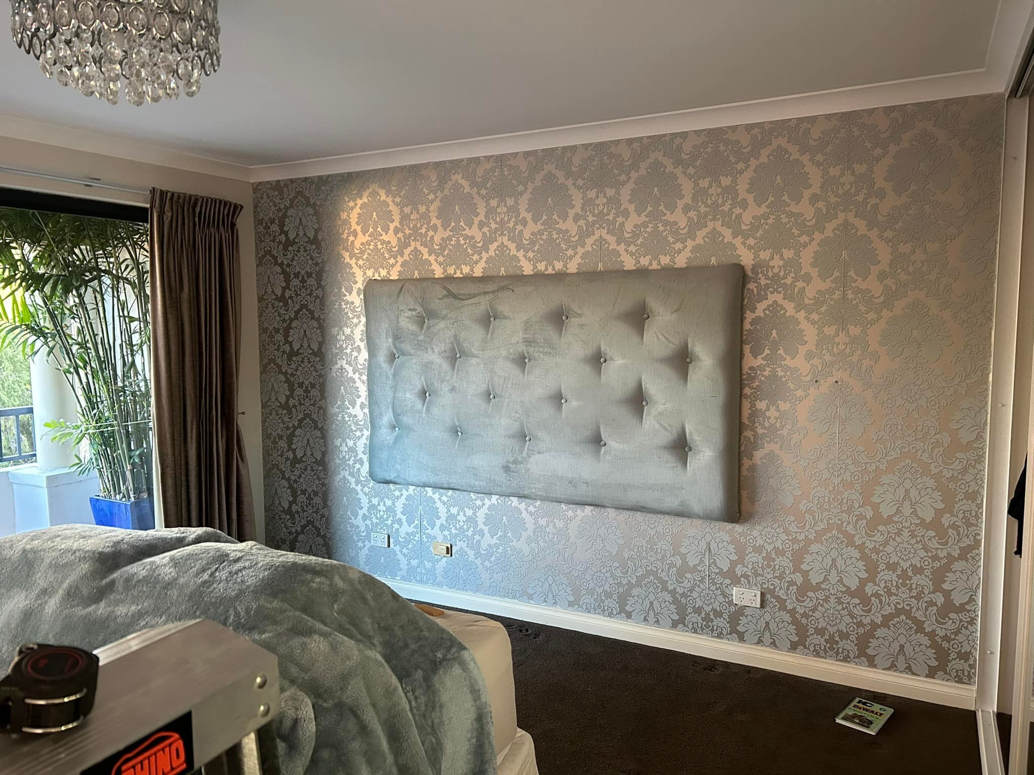Bedroom with damask wallpaper and a wall-mounted upholstered bedhead