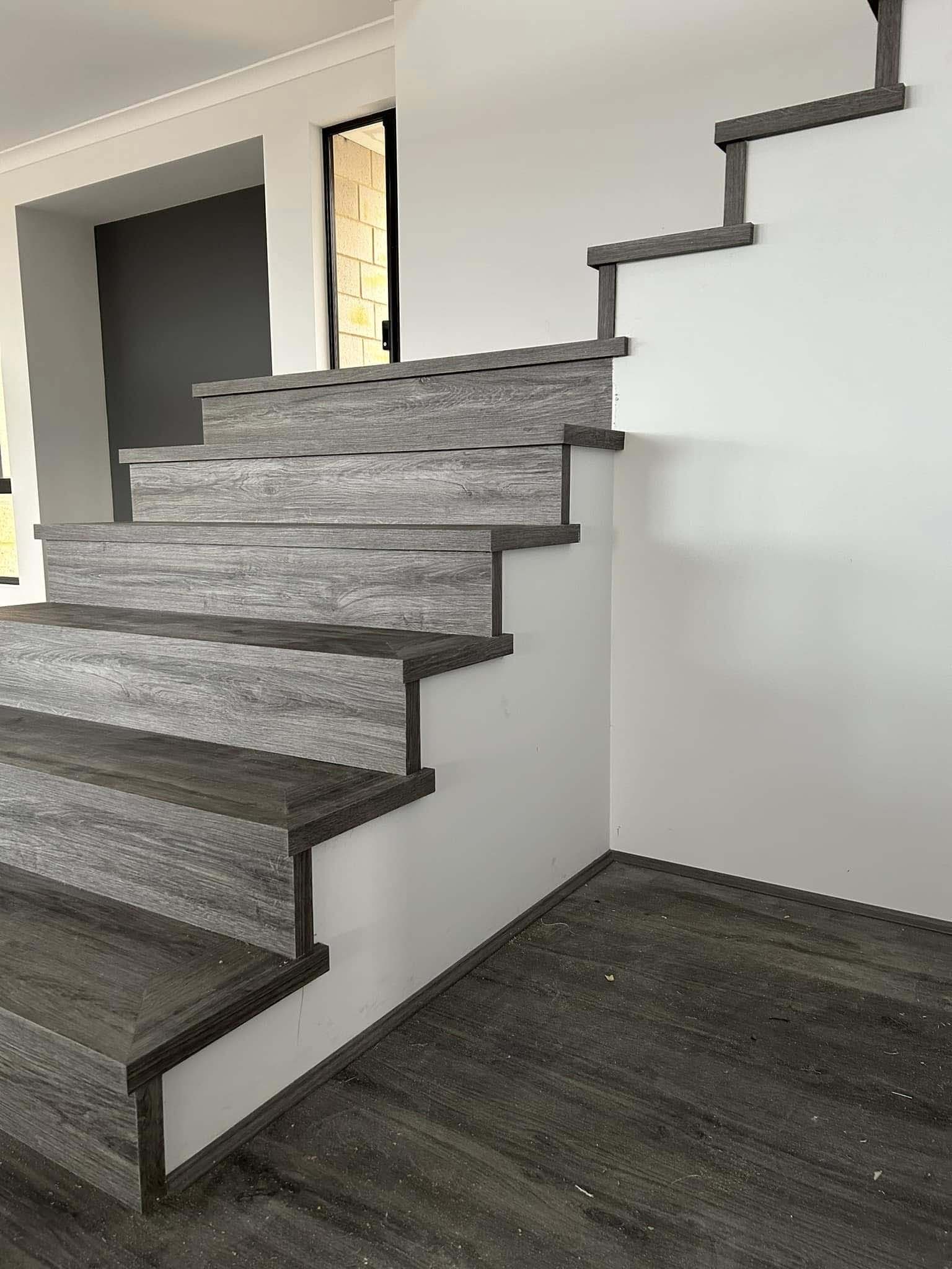 Staircase with grey timber-look treads beside a white wall