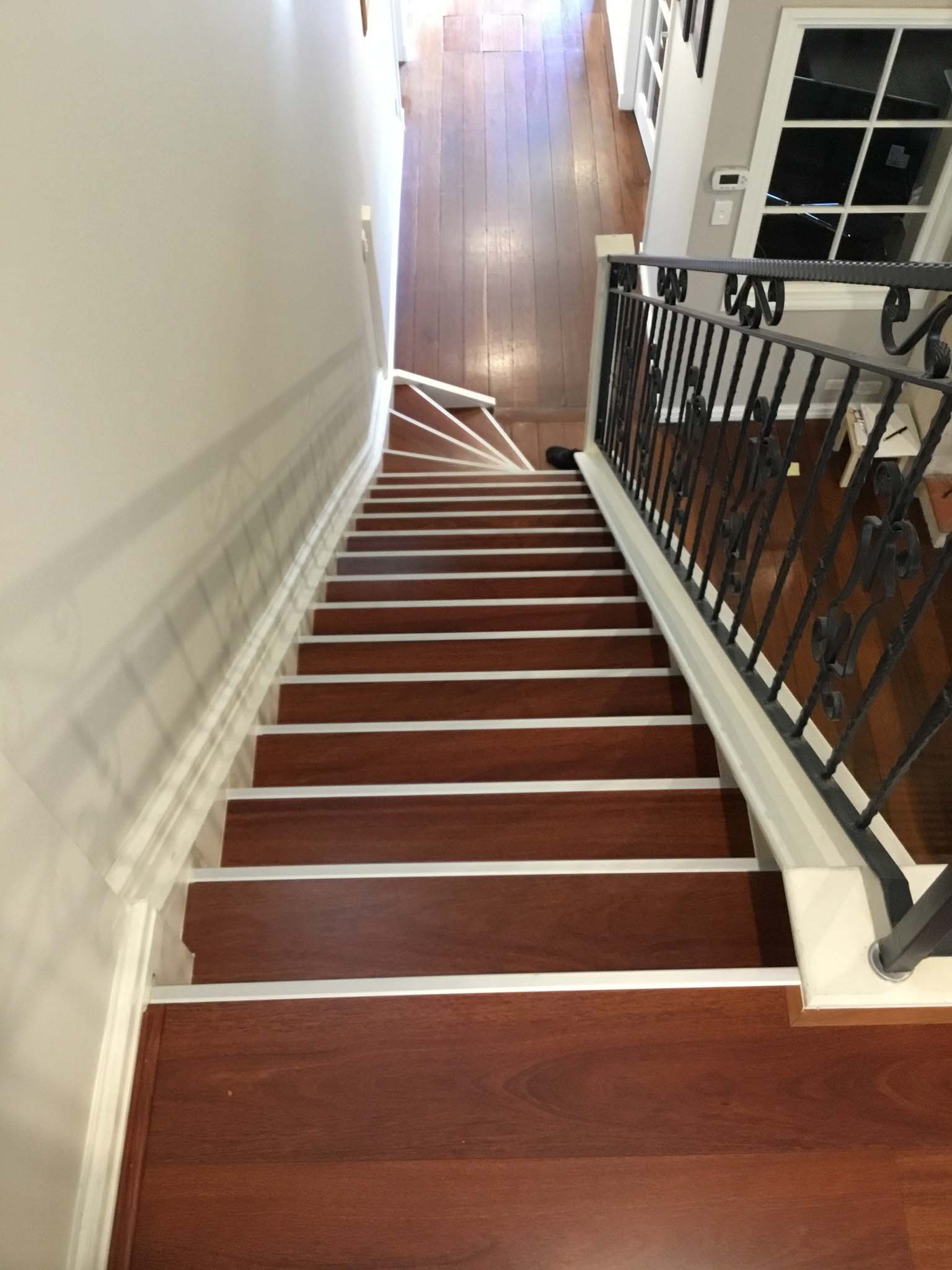 Long staircase with red timber treads, white nosings and black iron balustrade