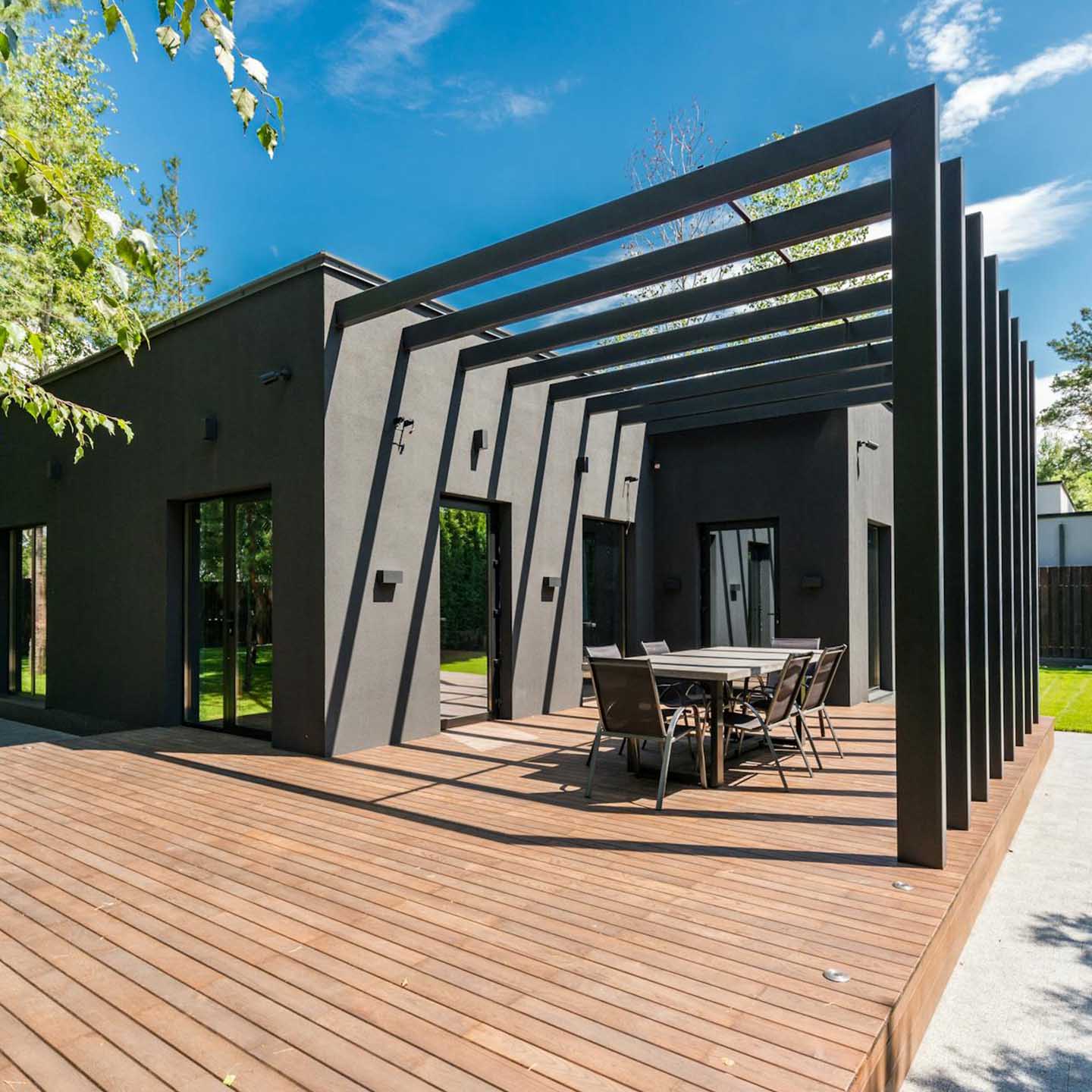 Black pergola over a timber deck with an outdoor dining setting