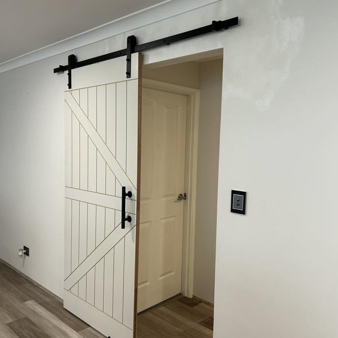 White barn door on a black sliding track beside a doorway