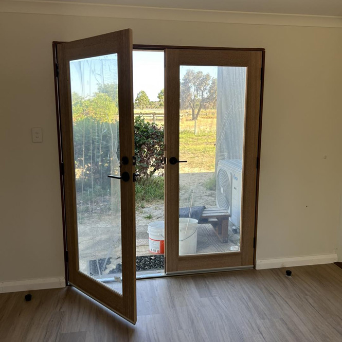 Timber-framed glass double doors opening onto a backyard
