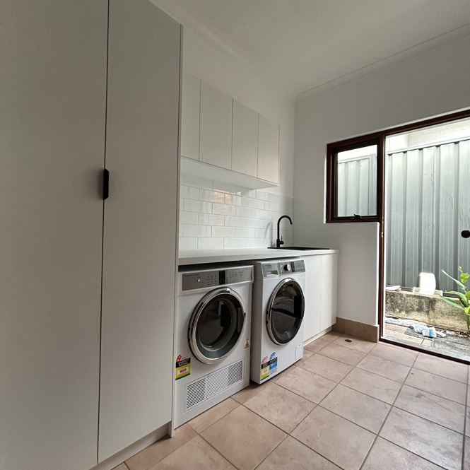 Laundry with white cabinetry, washer and dryer under the bench and tiled floor