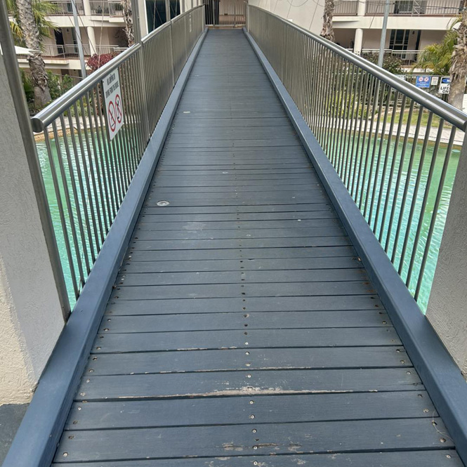 Long decked footbridge with metal railings over water