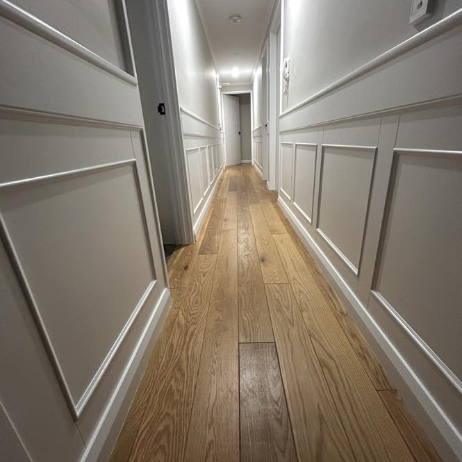 Hallway lined with white wainscoting panels and a timber floor